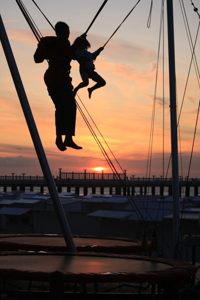 Bunge-Tarmpolin mit Mann und Kind im Sonnenuntergang