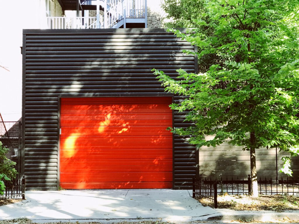 Rotes Garagentor in schwarzer Garage mit Baum
